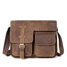 The Leather Business Travel Shoulder Bag is crafted from genuine cowhide leather and features a worn, vintage appearance with a fold-over flap secured by a high-quality alloy buckle strap. It includes two front pockets, a dark shoulder strap, and visible stitching that contribute to its rugged and classic look, making it ideal for business travel.