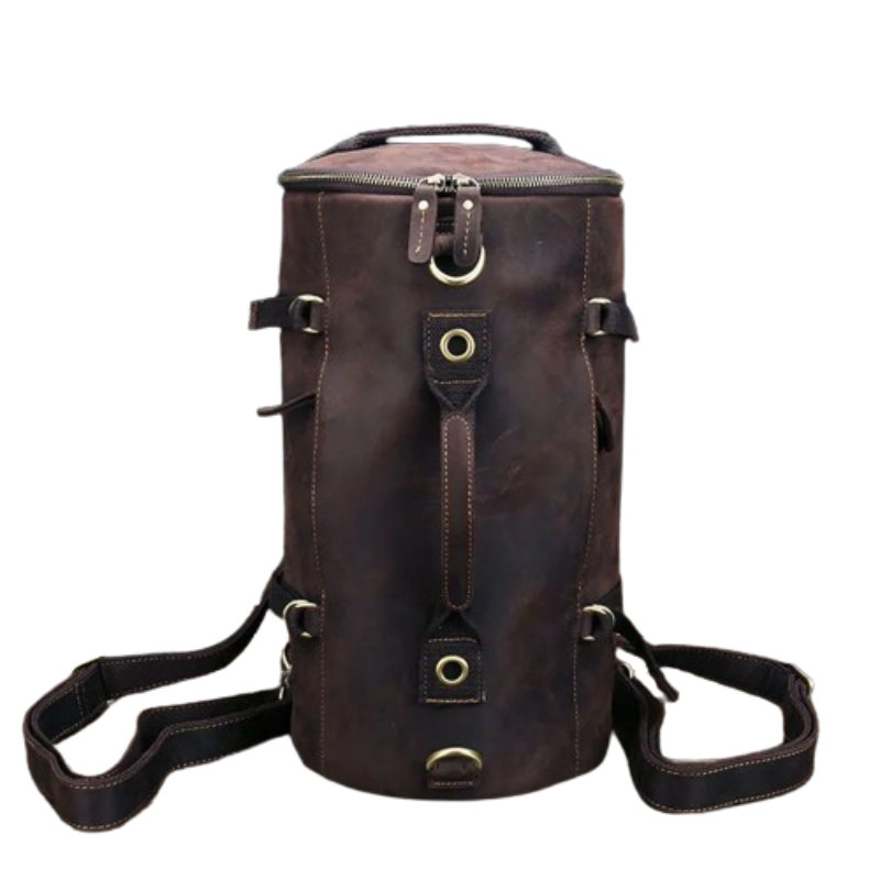 The Vintage Leather Travel Backpack is a brown leather cylindrical backpack meticulously crafted from genuine cowhide leather. It boasts multiple straps, buckles, and brass accents, ideal for the stylish traveler. This bag has a rugged vintage appearance and includes a top handle, two adjustable shoulder straps, and a zipper closure at the top.