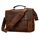 The Leather 14" Briefcase Shoulder Bag is crafted from genuine brown cowhide and features a front flap secured by two buckle straps. It boasts a sturdy top handle and an adjustable shoulder strap with a brass clasp detail, providing both functionality and style. With its classic and rugged design, this bag is perfect for carrying documents and personal items in professional style.